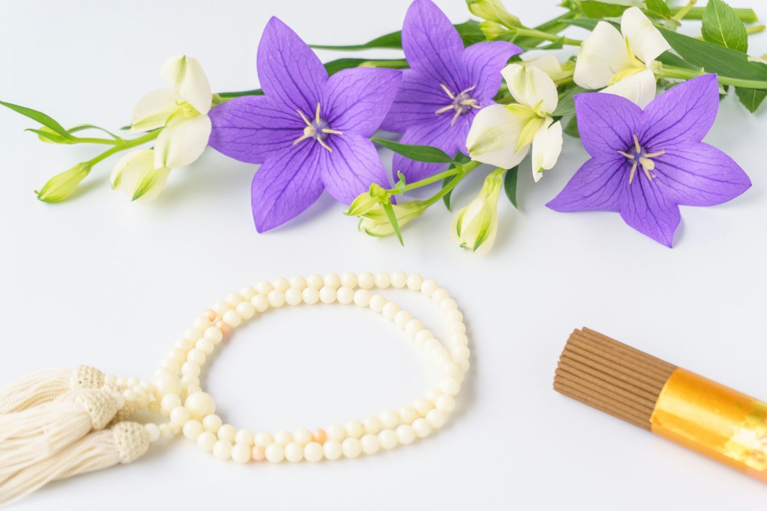 Un'aranjamento sereno con fiori viola e un braccialetto di perle bianche
