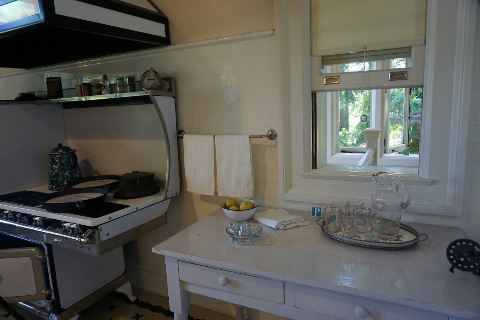 Intérieur de cuisine lumineux avec table blanche présentant des fruits et un plat en verre fenêtre de cuisine reflétant la vue extérieure
