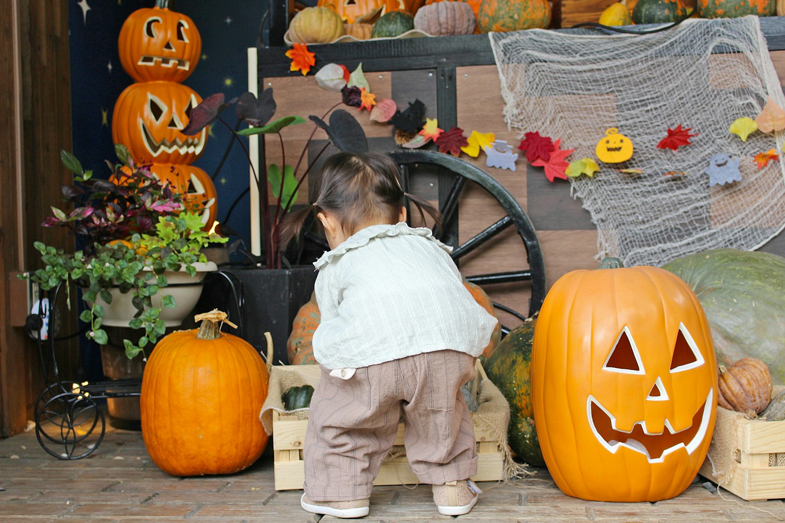 Un bambino che gioca davanti a decorazioni di Halloween con zucche e foglie autunnali