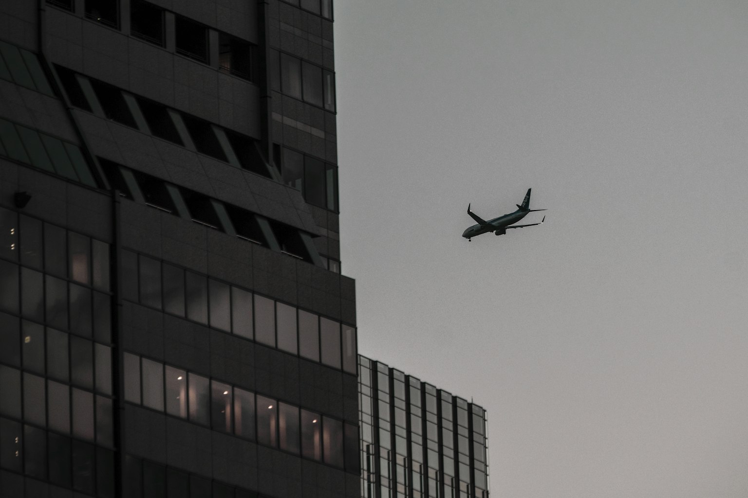 Silhouette di un aereo che vola vicino a un edificio al crepuscolo