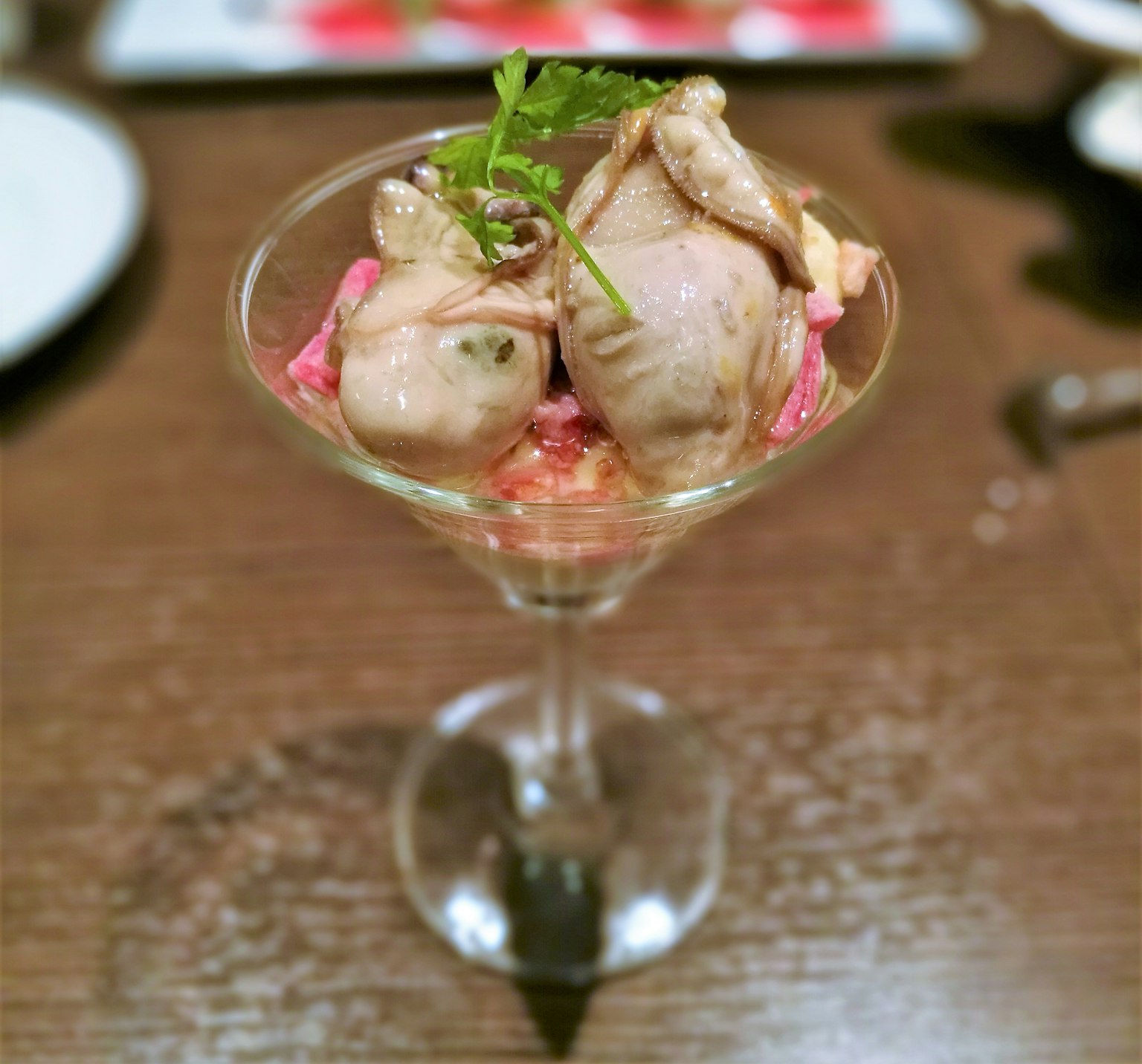 Dish served in a glass cocktail bowl featuring two birds garnished with herbs