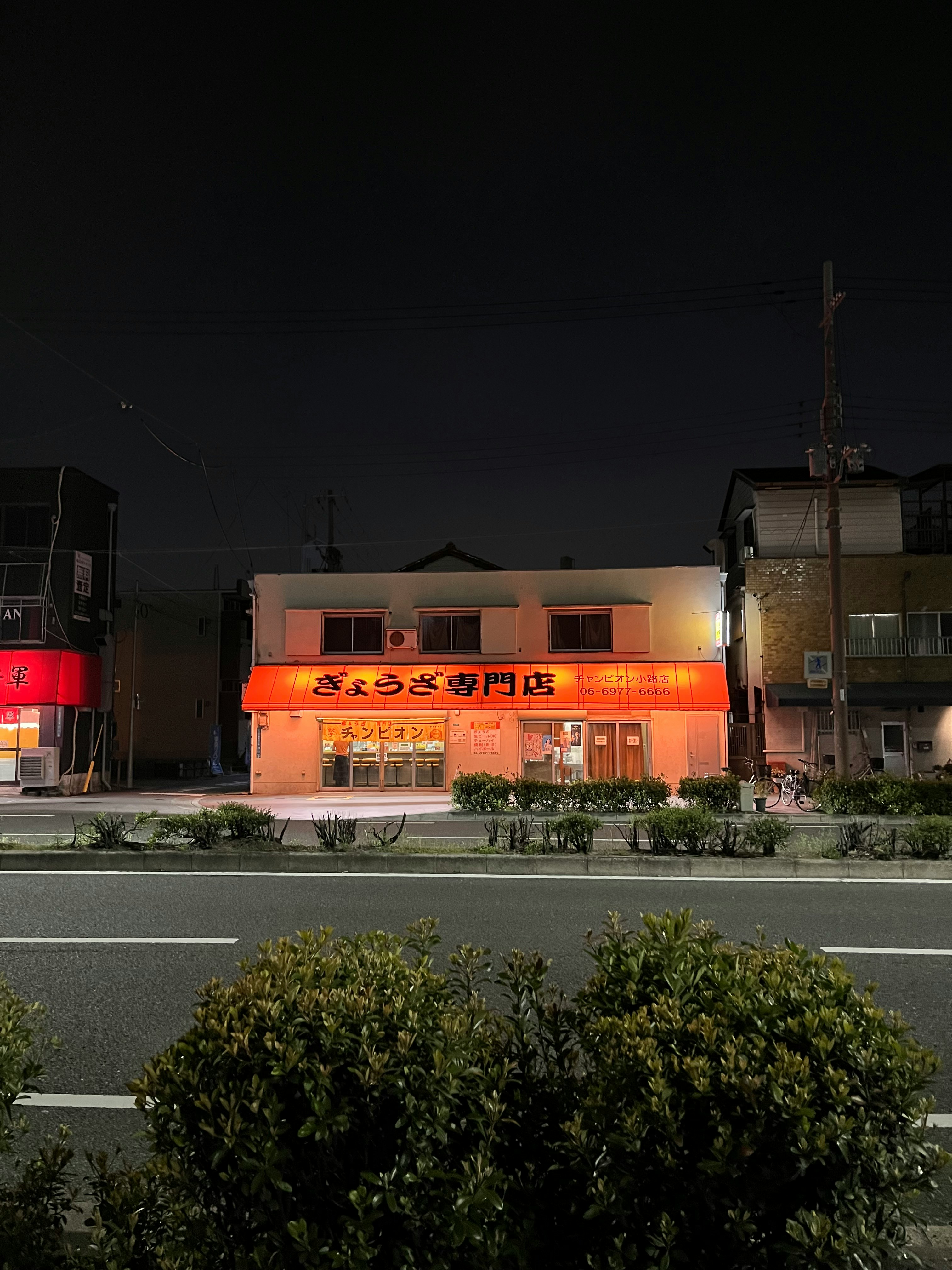夜の道路沿いにある赤い看板の店先