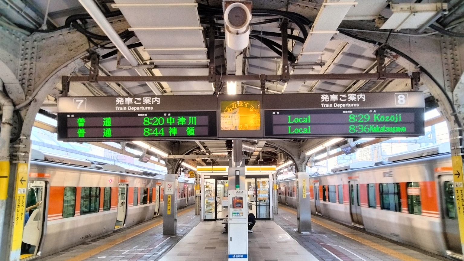 ป้ายดิจิตอลและรถไฟที่รออยู่ที่ชานชาลาสถานี