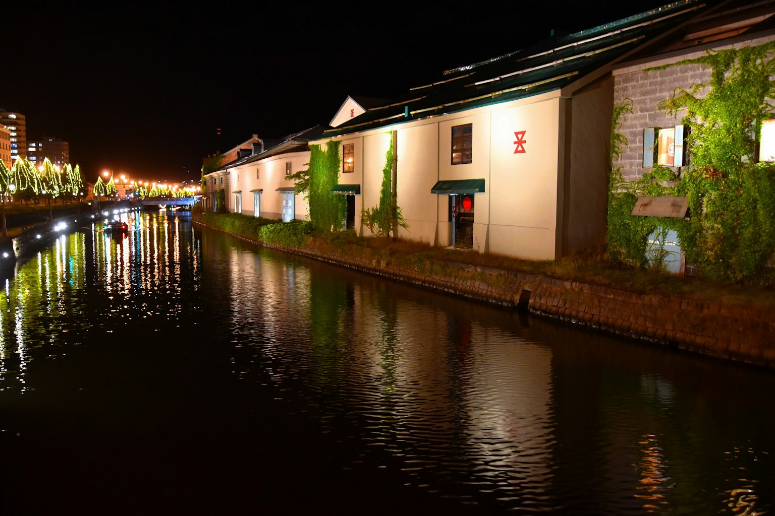 Vista nocturna de edificios a lo largo de un canal reflejándose en el agua