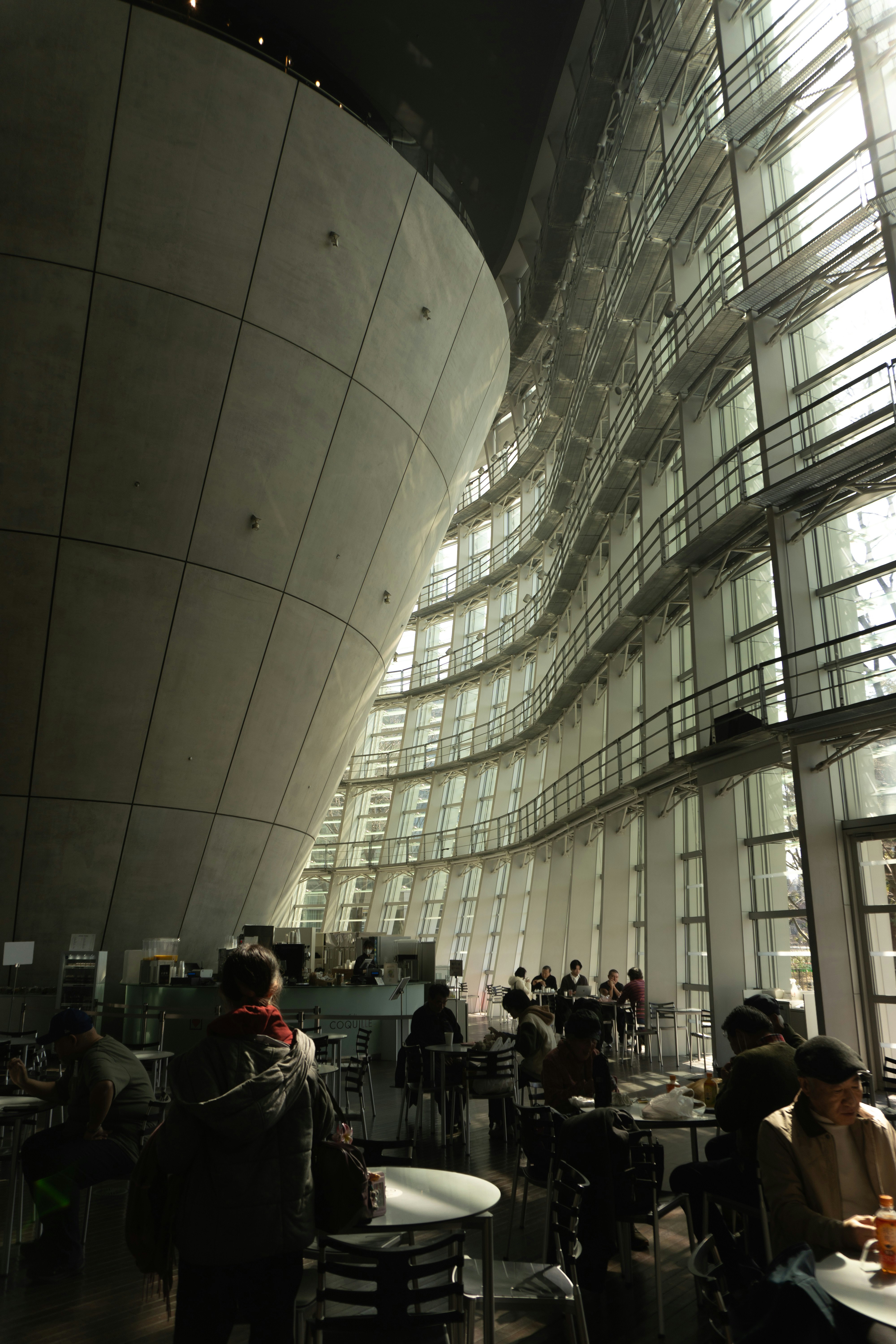 orang-orang menunggu di aula gedung dengan fasad melengkung