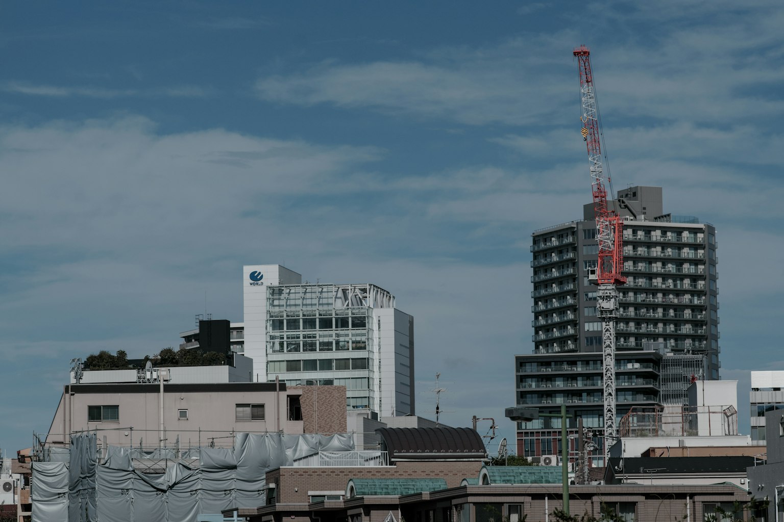 Stadtlandschaft mit Gebäuden und einem Kran unter blauem Himmel