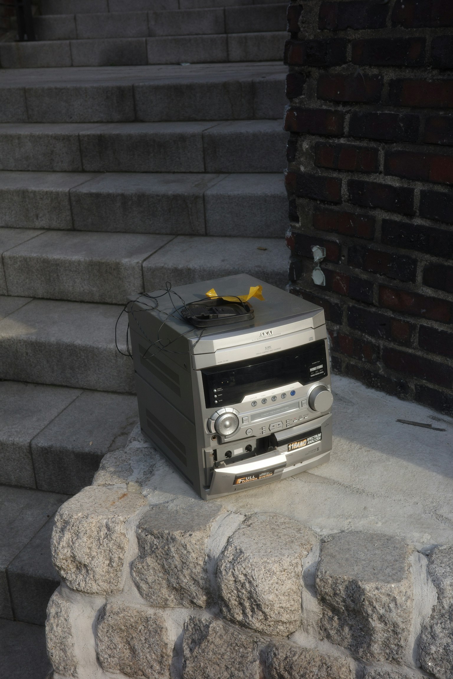 An old cassette player placed on a stone pedestal beside stairs
