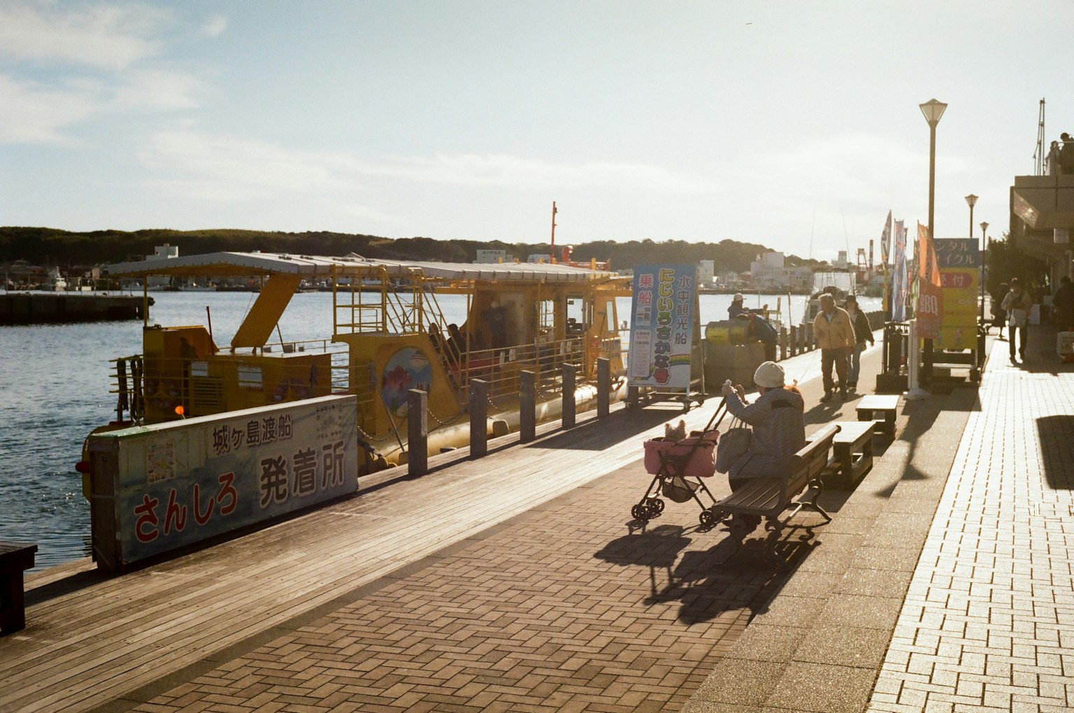 People on a lively riverfront walkway with yellow trucks