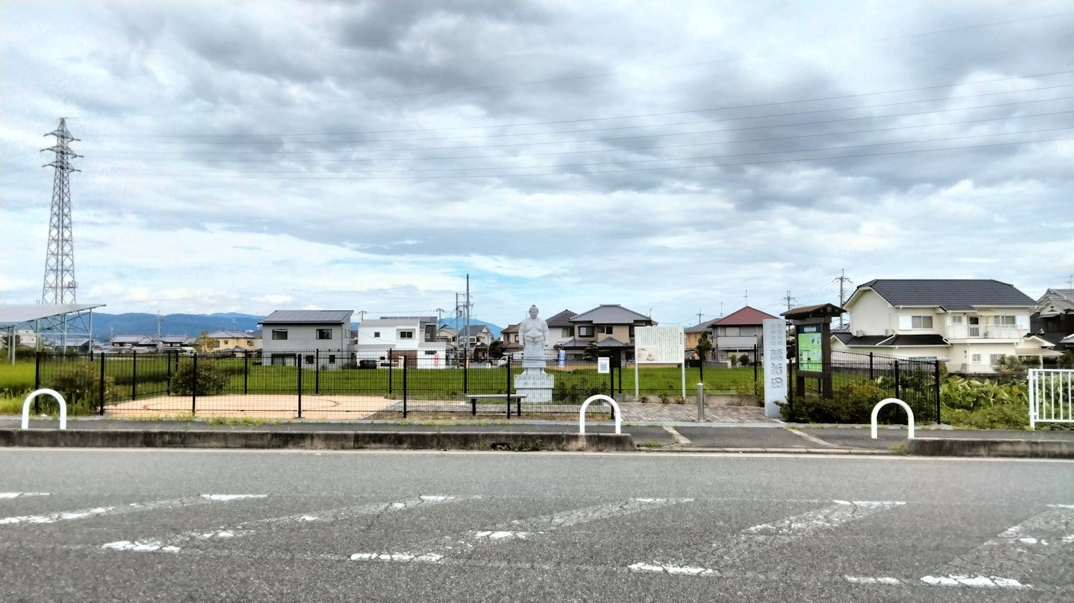 A landscape featuring residential houses and a park under a cloudy sky