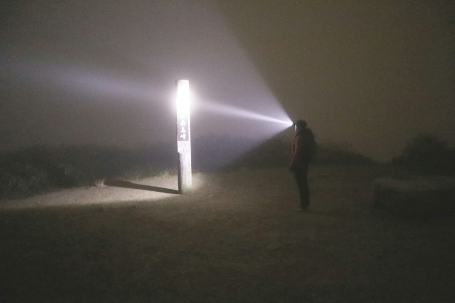 Person mit Taschenlampe im Nebel mit einem hellen Lichtstrahl