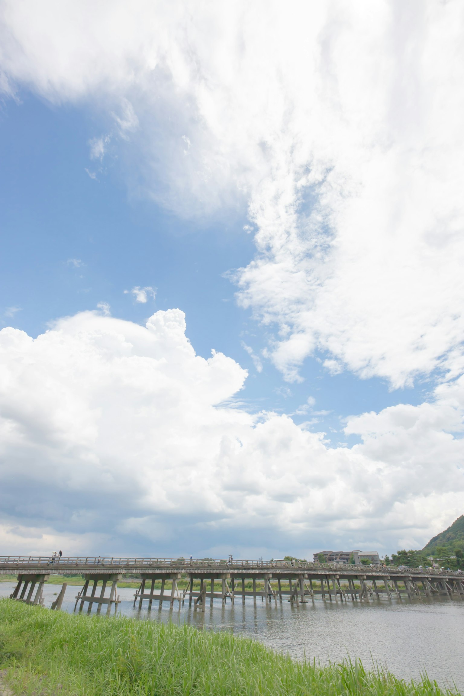 Holzbrücke unter einem blauen Himmel mit fluffigen weißen Wolken