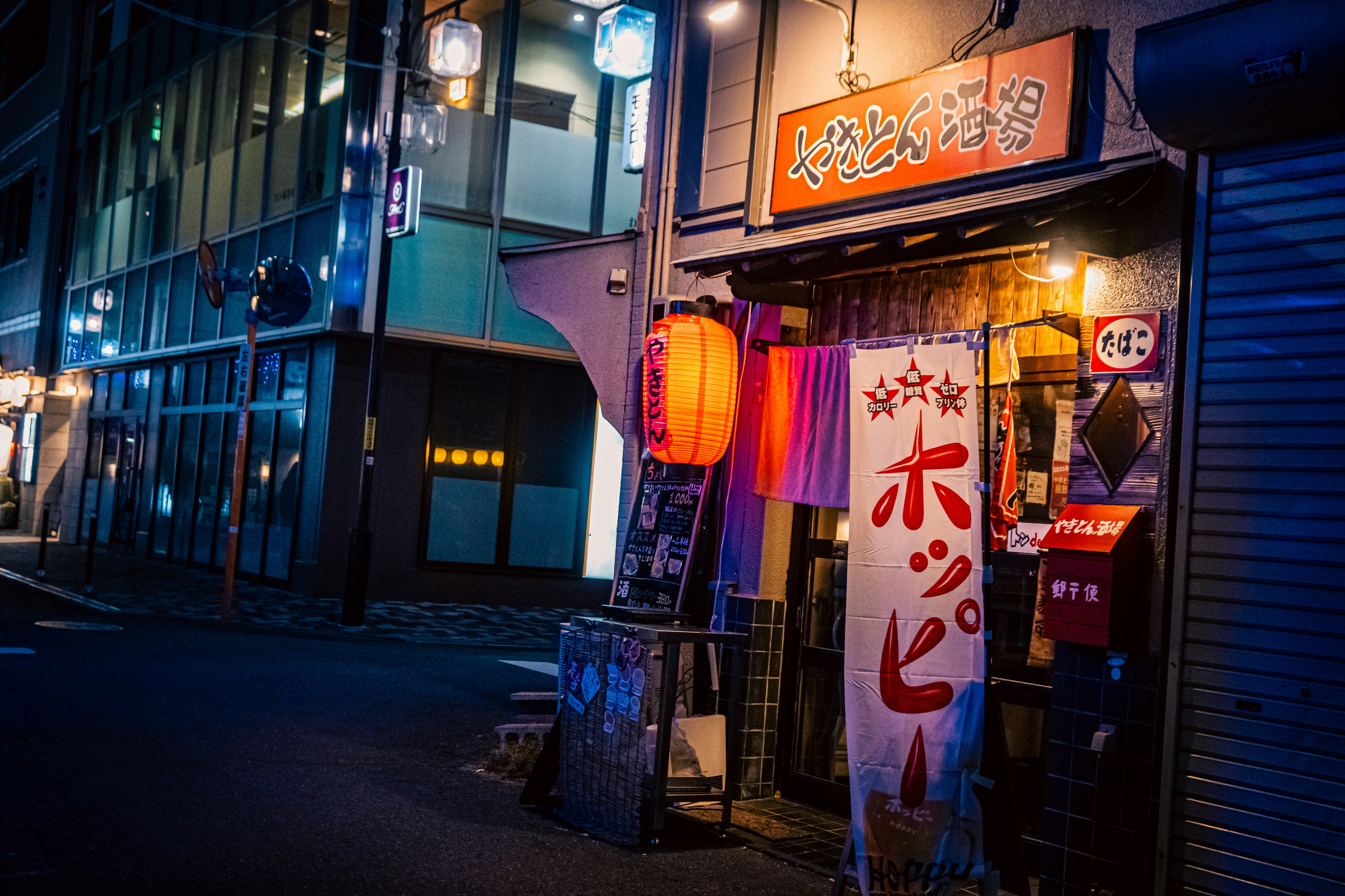 路地の飲食店の提灯と暖色の灯りが並ぶ夜の街角