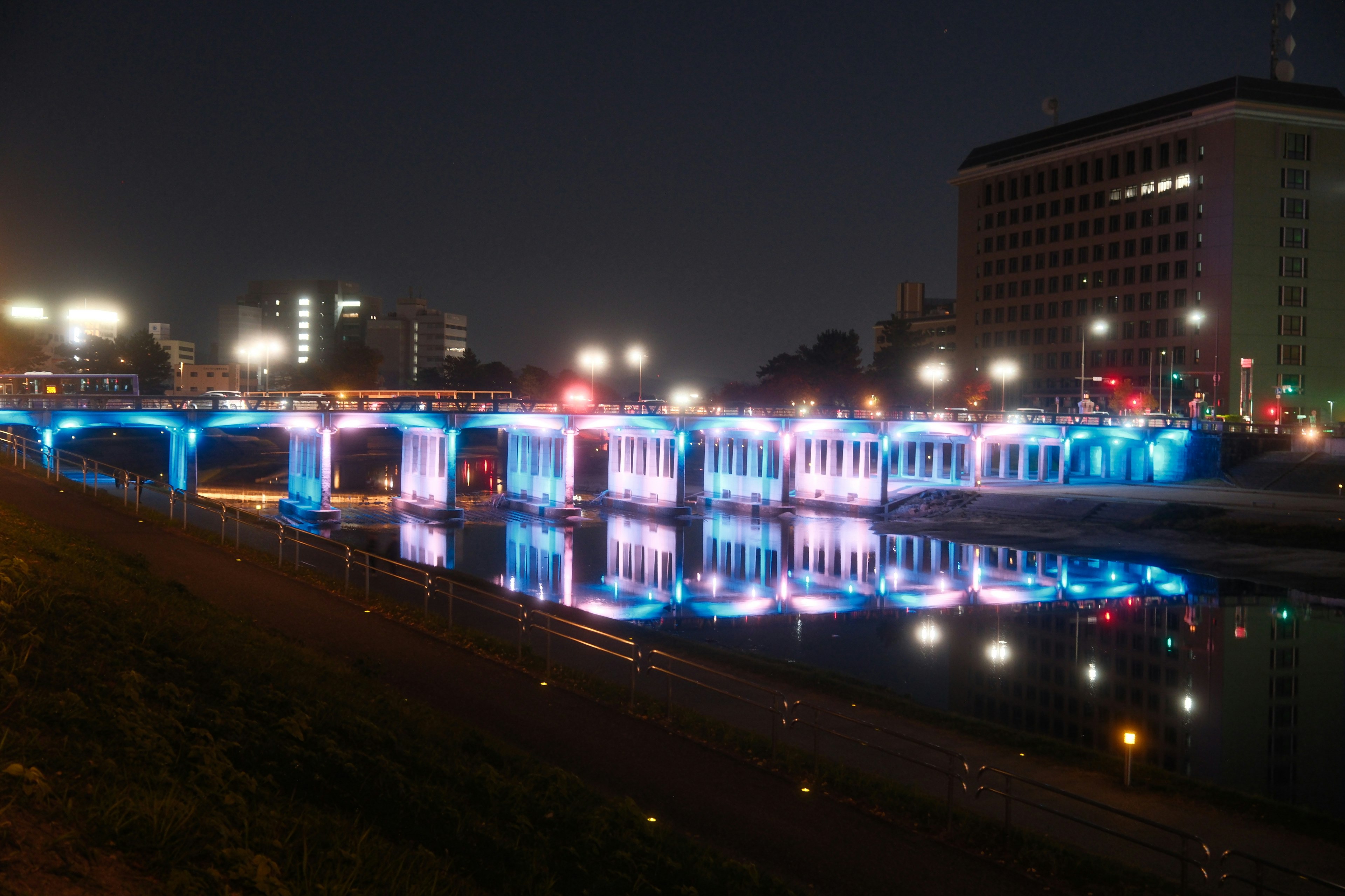 夜景のライトアップされた川沿いの遊歩道と橋