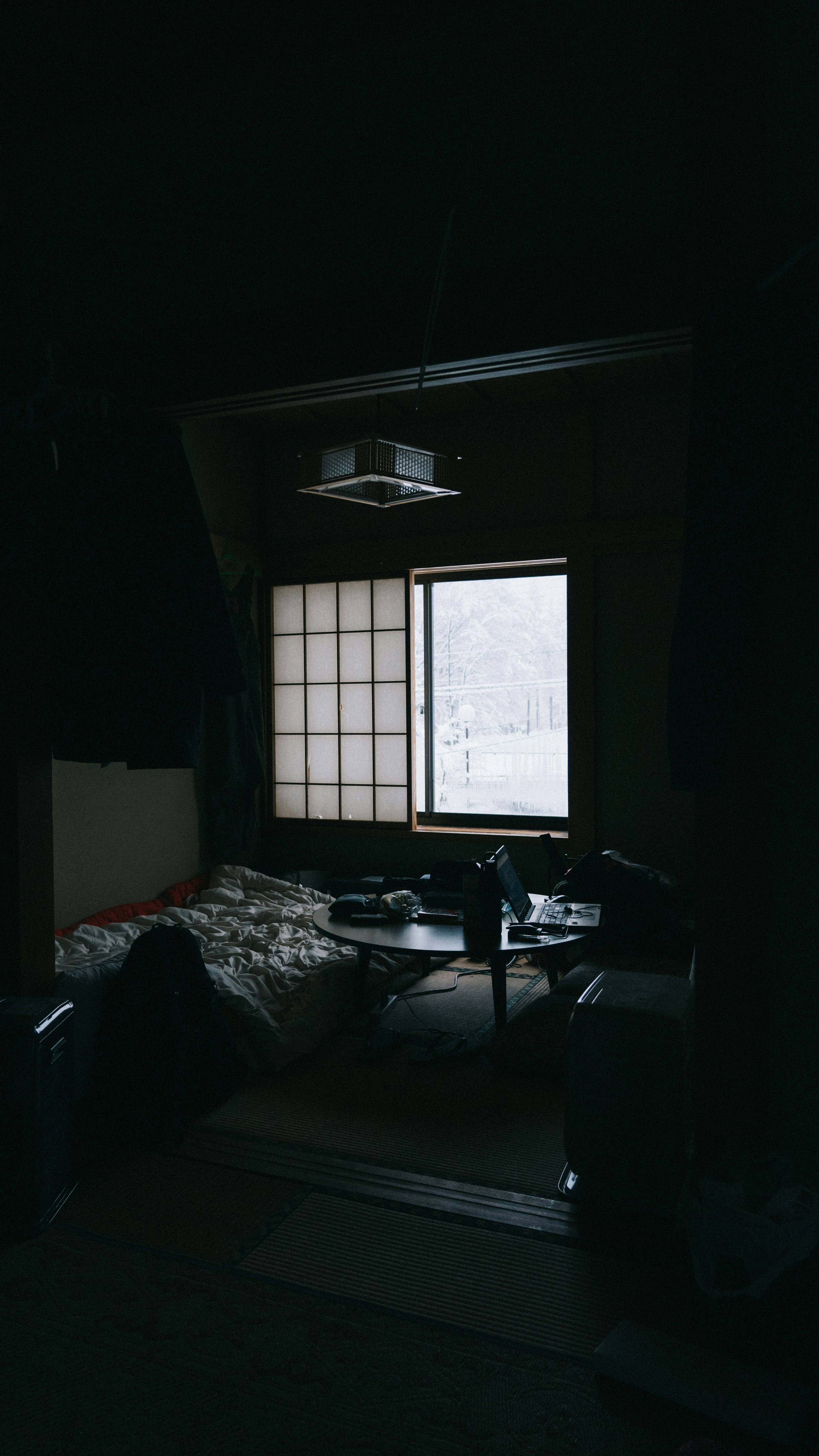 雪国の宿の部屋で窓から差す自然光と机の上の散らかった書類