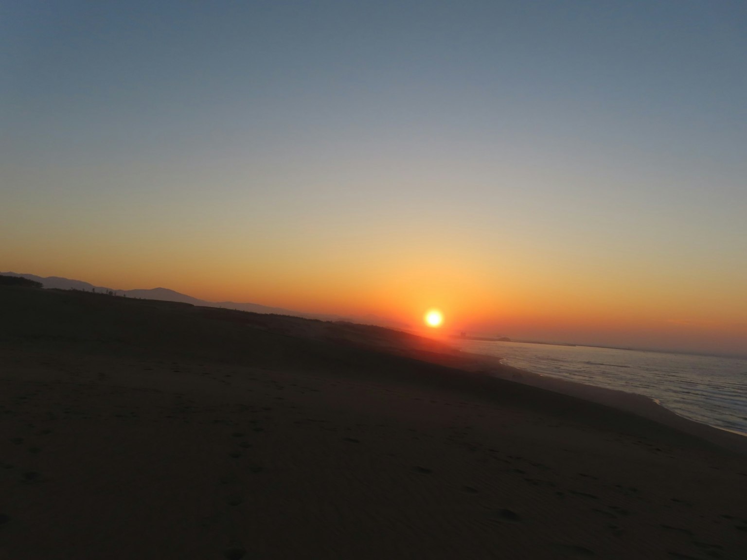 Puesta de sol sobre la costa con mar tranquilo