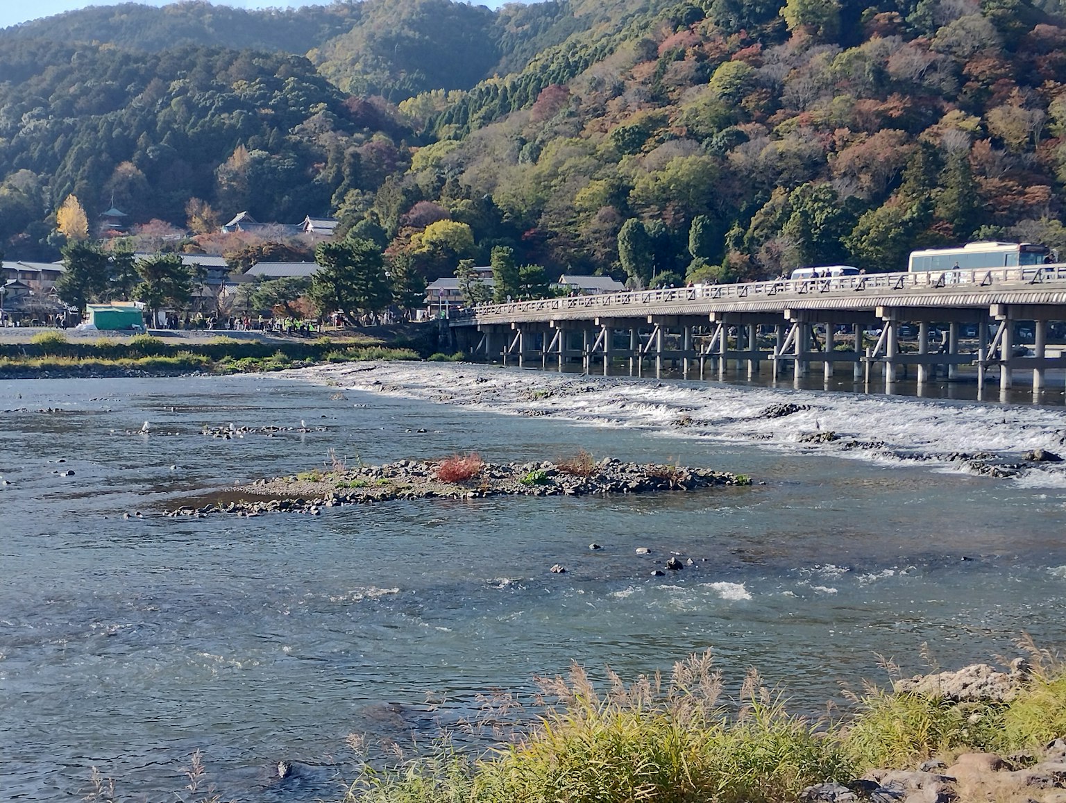 ทิวทัศน์ของแม่น้ำที่มีสะพานไม้และใบไม้ฤดูใบไม้ร่วงบนเนินเขา