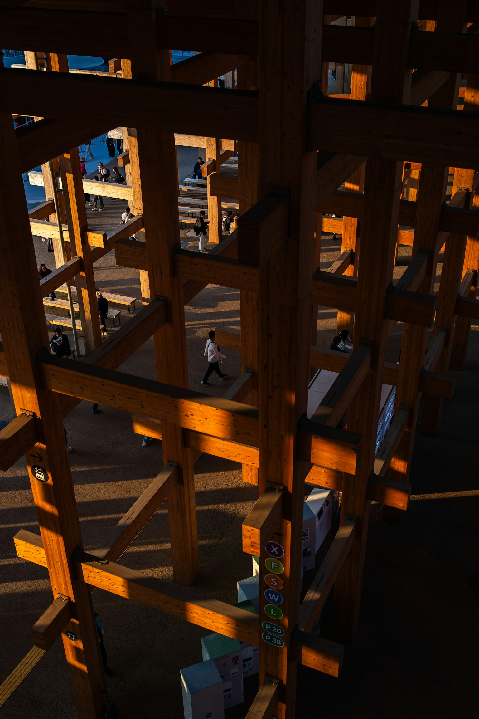 Person walking through wooden structure casting shadows in sunset light