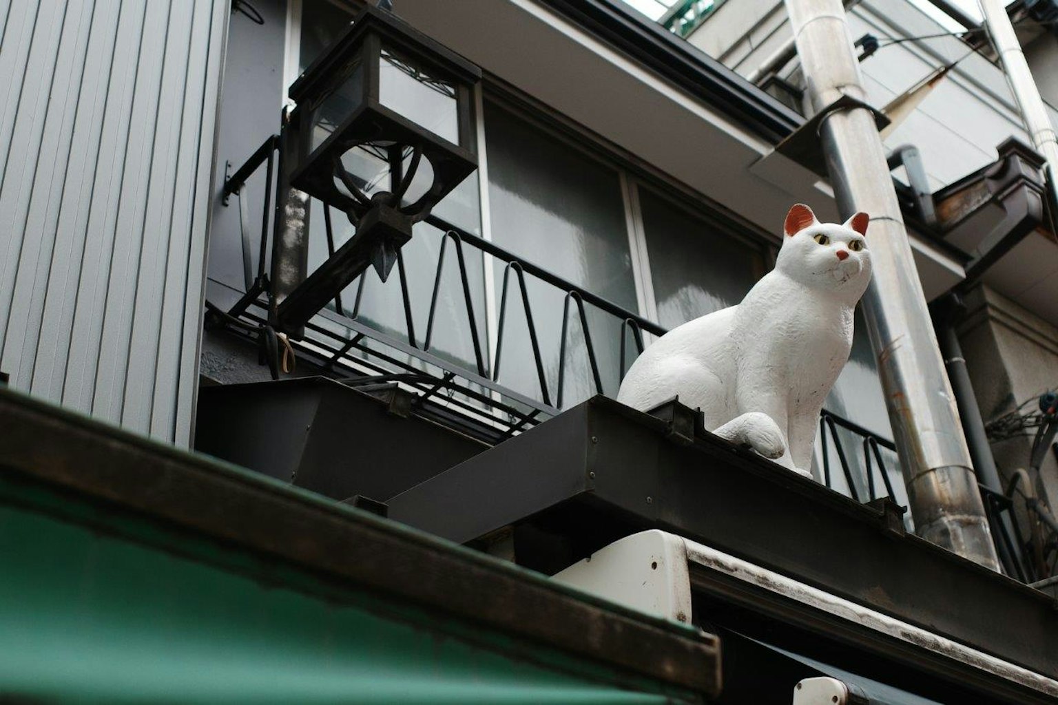 Una scultura di gatto bianco è posizionata su un balcone
