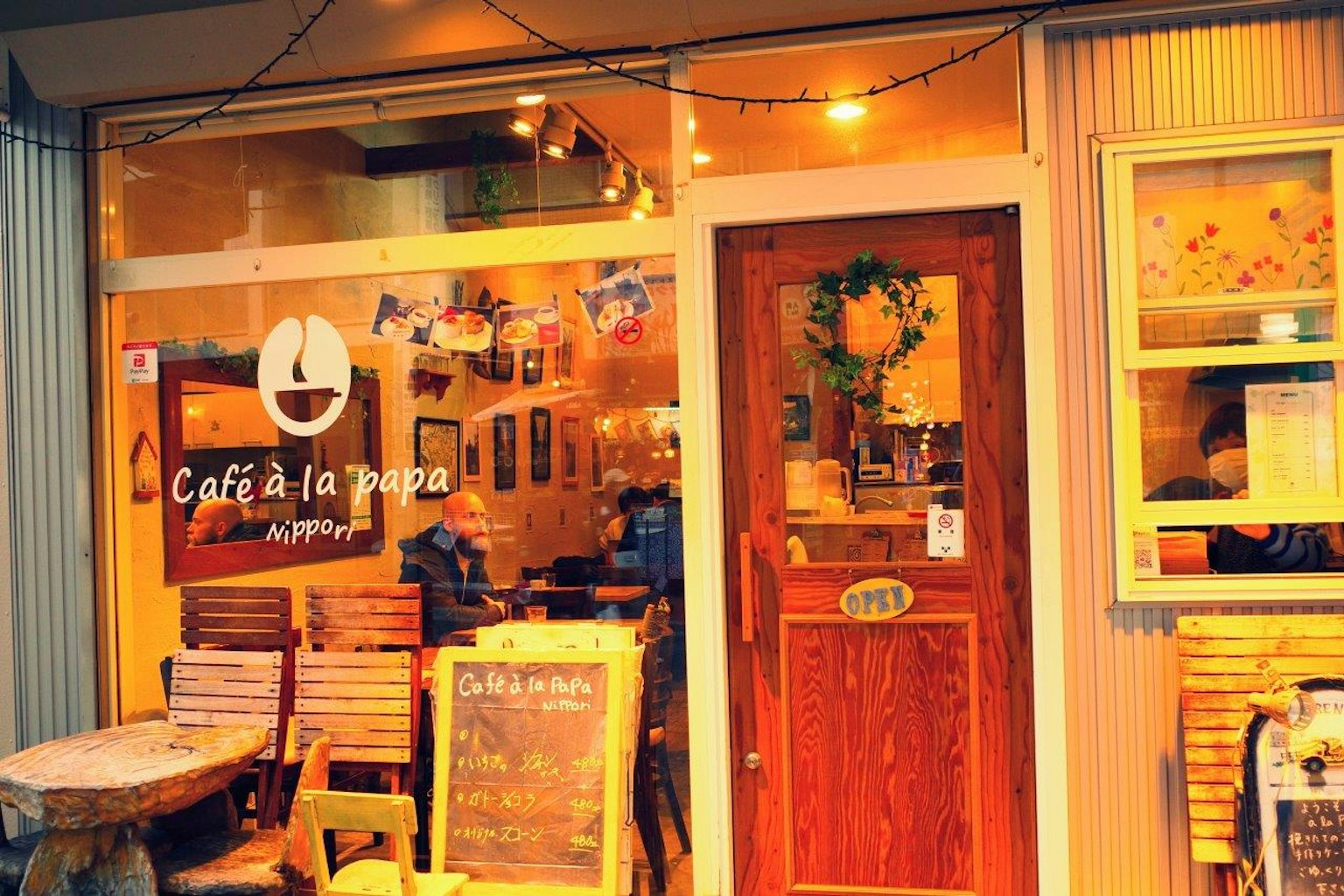 Vue extérieure d'un café avec un éclairage chaleureux et une porte en bois