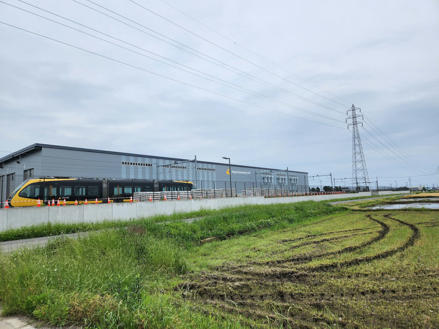 Ansicht einer Fabrik mit einem Zug in der Nähe grünes Gras und sichtbare Stromleitungen