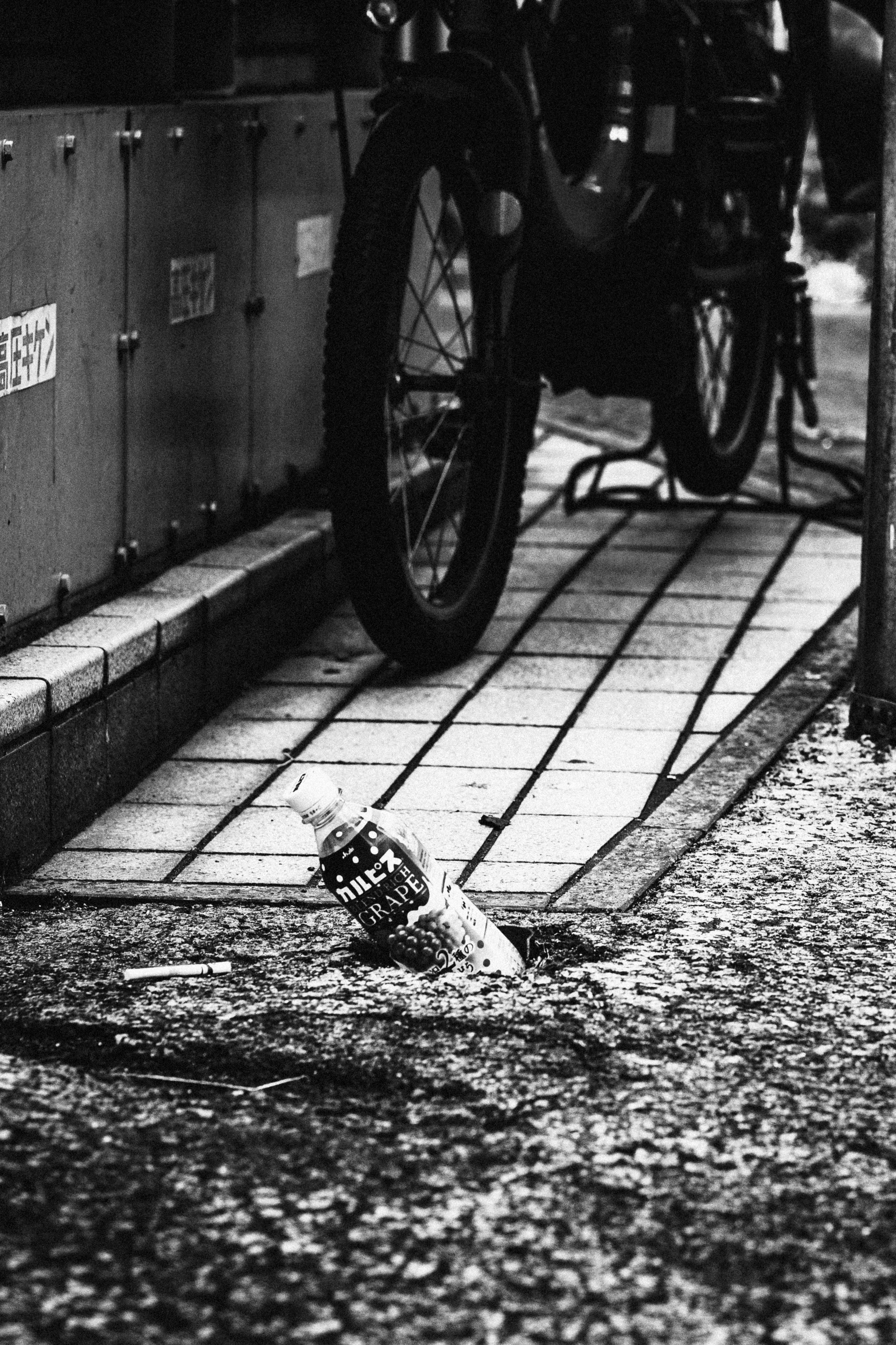 路地の石畳に置かれた自転車の車輪と看板のある壁