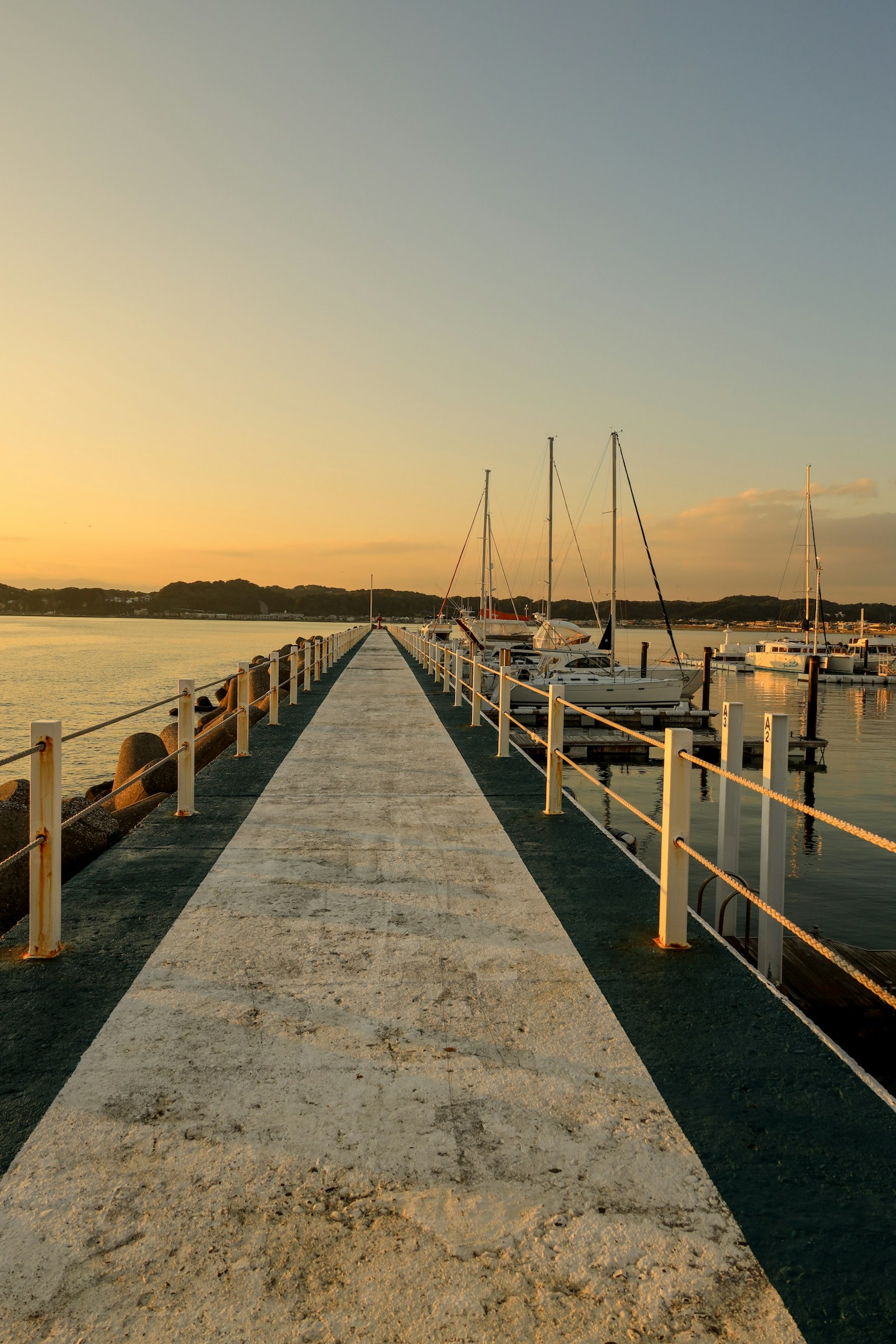 Ruhiger Steg, der zu Segelbooten bei Sonnenuntergang führt