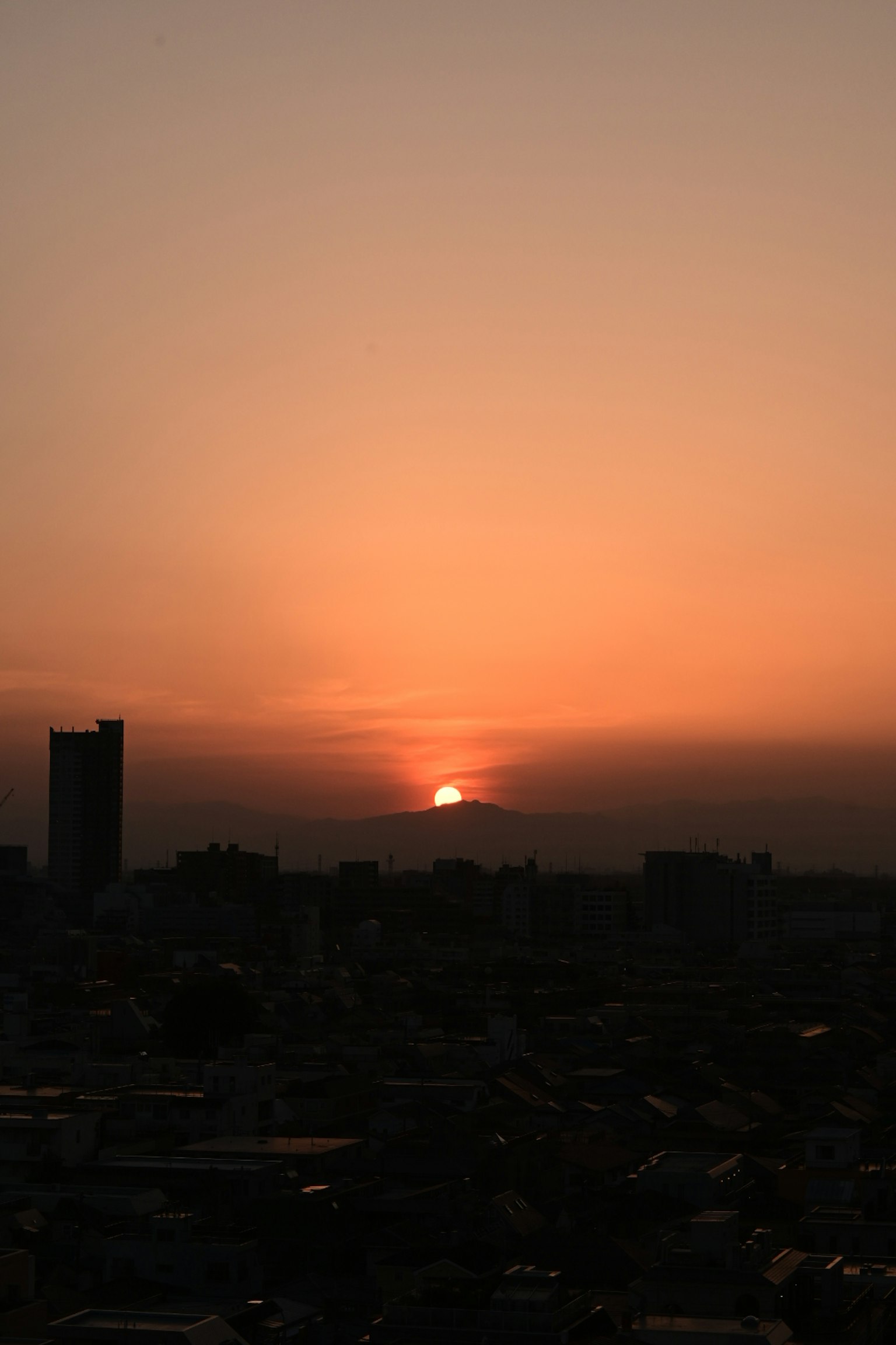 Horizonte de ciudad al atardecer con cielo naranja y edificios en silueta