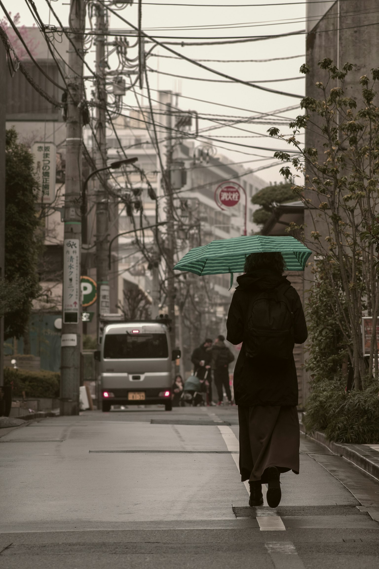 一位女性在街道上走，手持伞
