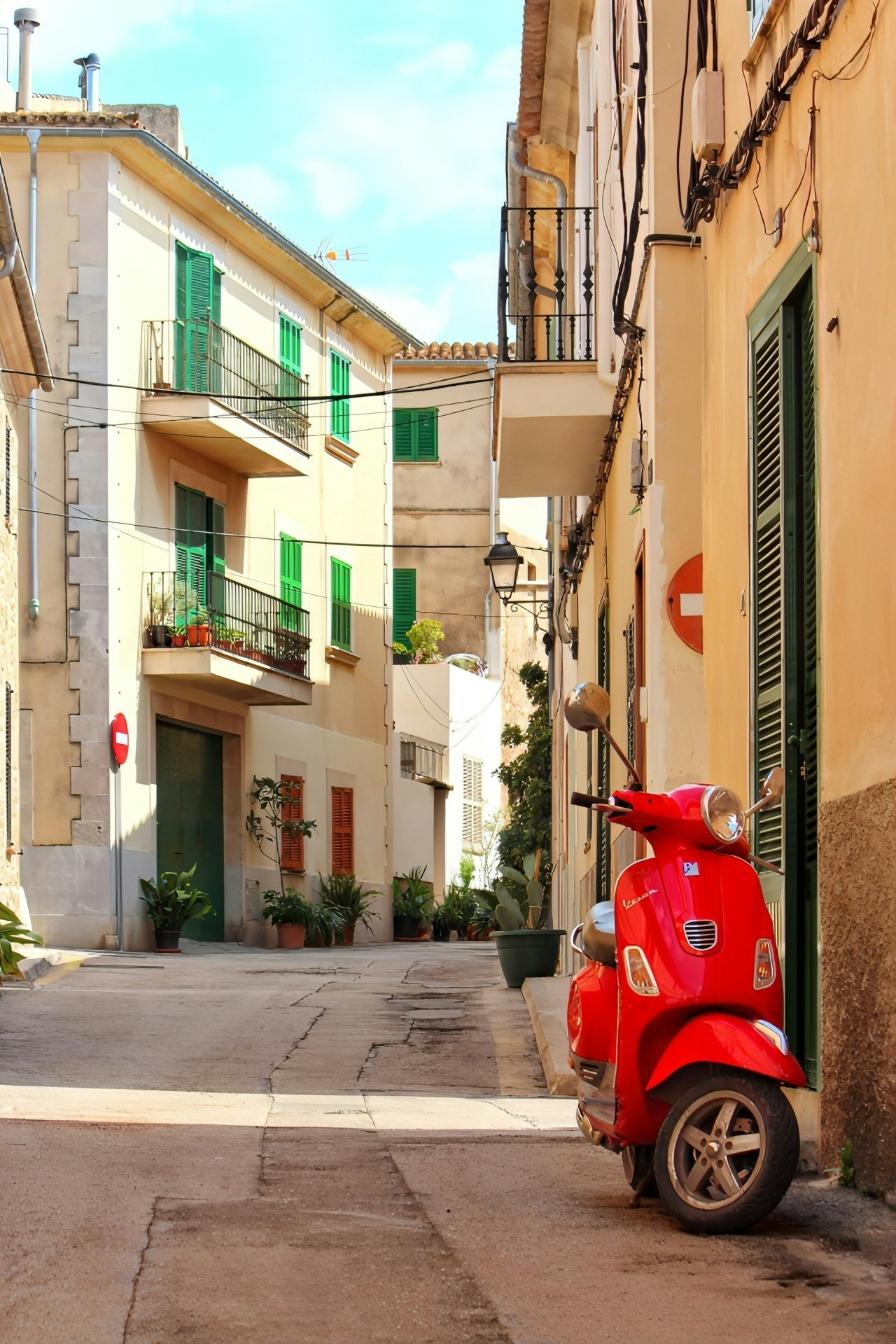 Red Vespa parked in a narrow alley on Mallorca with surrounding buildings