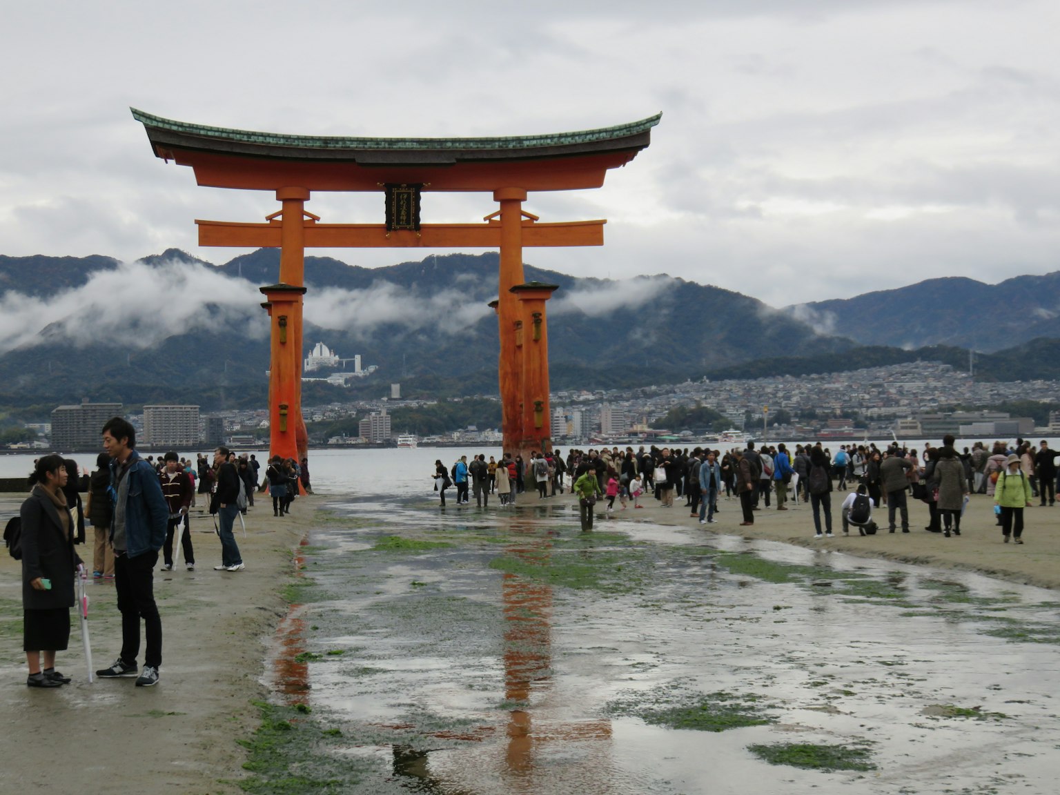 Vista de la puerta torii icónica del santuario de Itsukushima con turistas