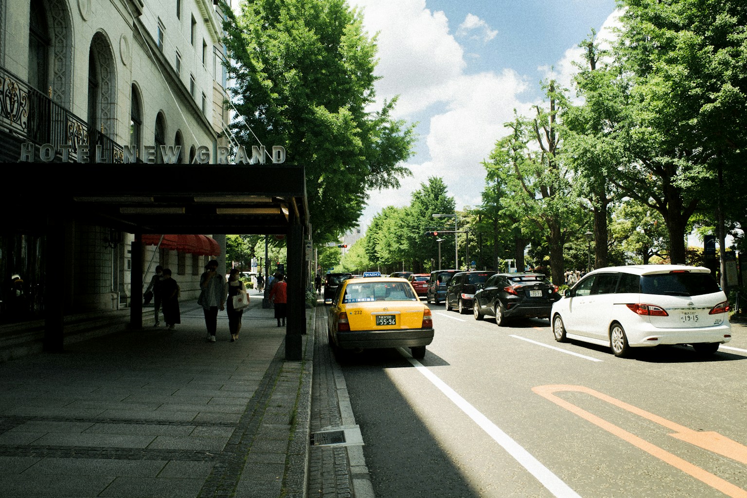 Une scène de rue animée avec des arbres luxuriants et un taxi au premier plan