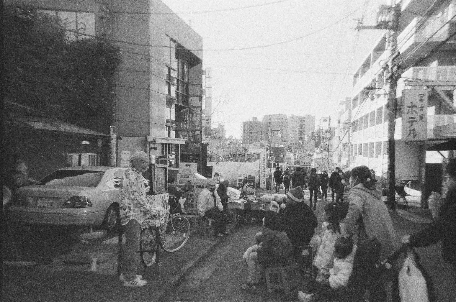 bicycles and people lined along a narrow shopping alley storefront