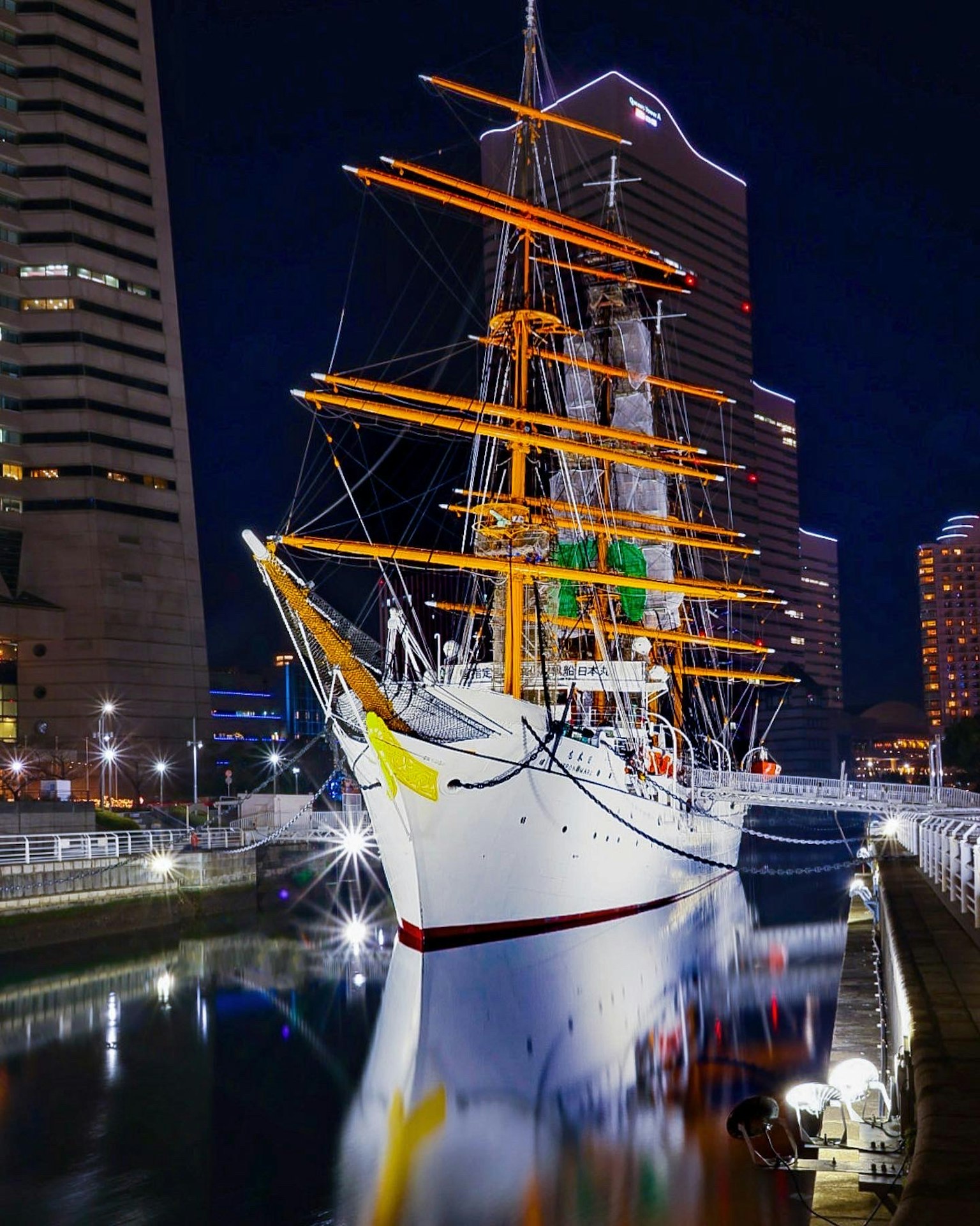 Beautiful sailing ship docked at night with reflections in the water