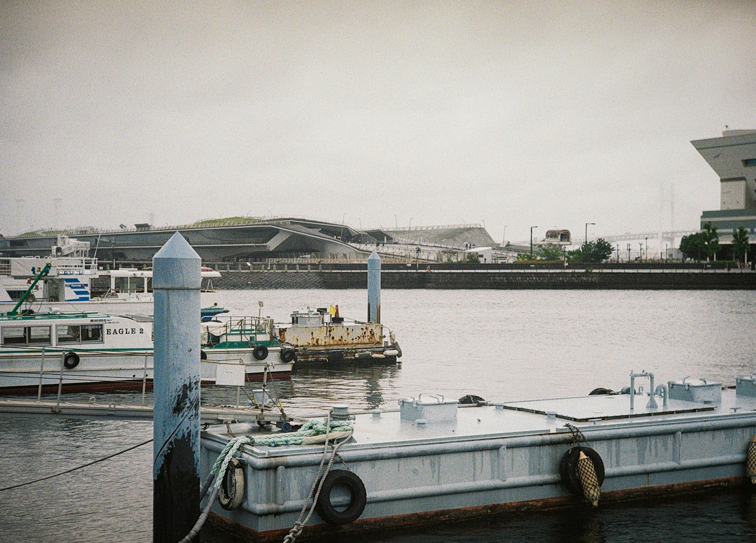 Boats docked at a harbor with calm water and a cloudy sky