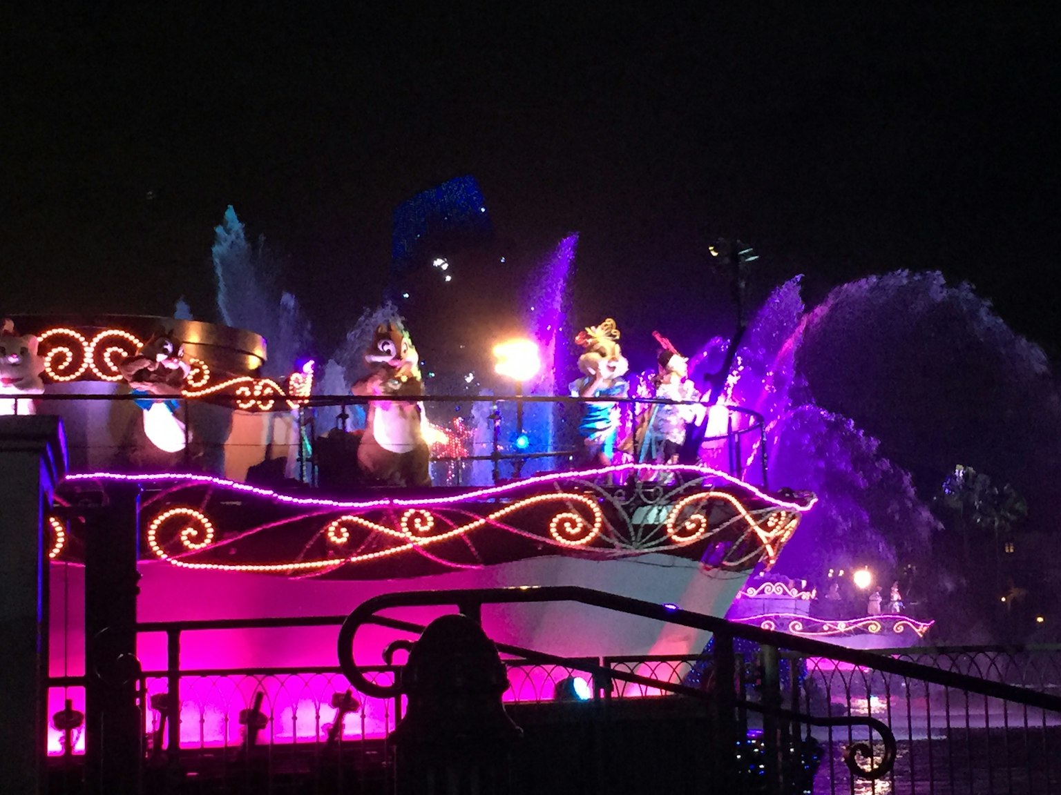 Barco iluminado colorido con personajes durante un desfile nocturno
