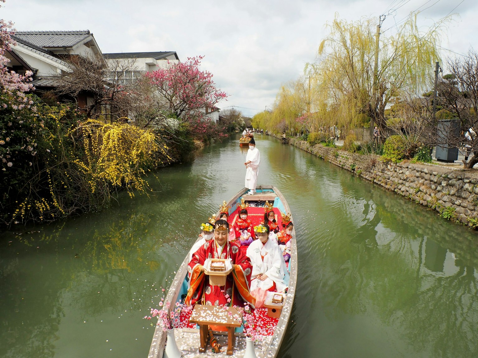 Perahu tradisional Jepang dengan orang-orang berpakaian kimono di saluran yang indah