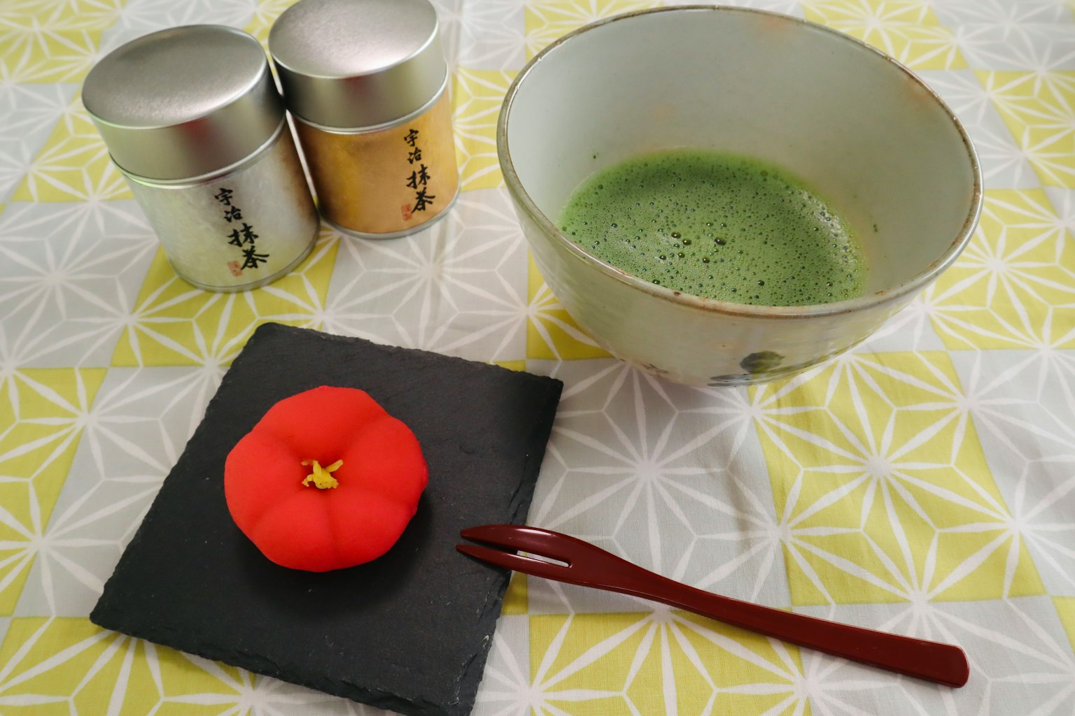 A table setting featuring green tea and a red Japanese sweet