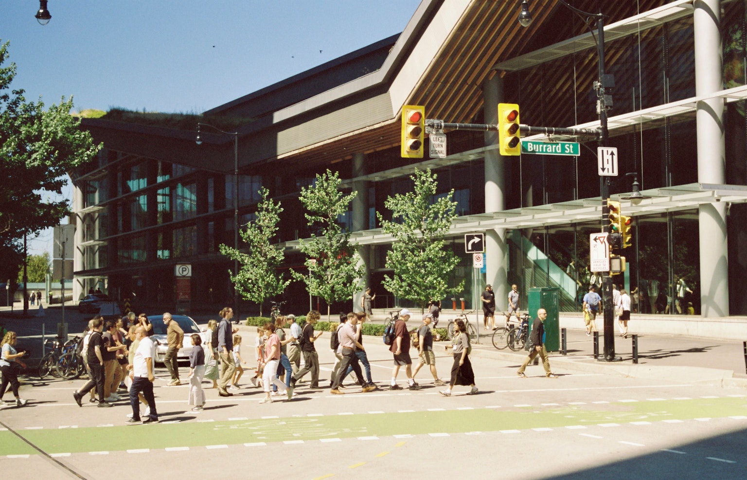 Foule de personnes marchant dans une rue avec une architecture moderne et des arbres verts
