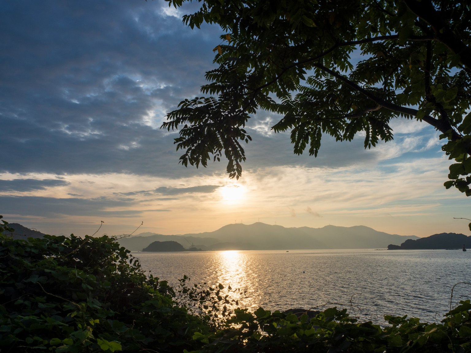 Pemandangan indah dengan matahari terbenam yang memantul di danau pohon hijau dan siluet gunung