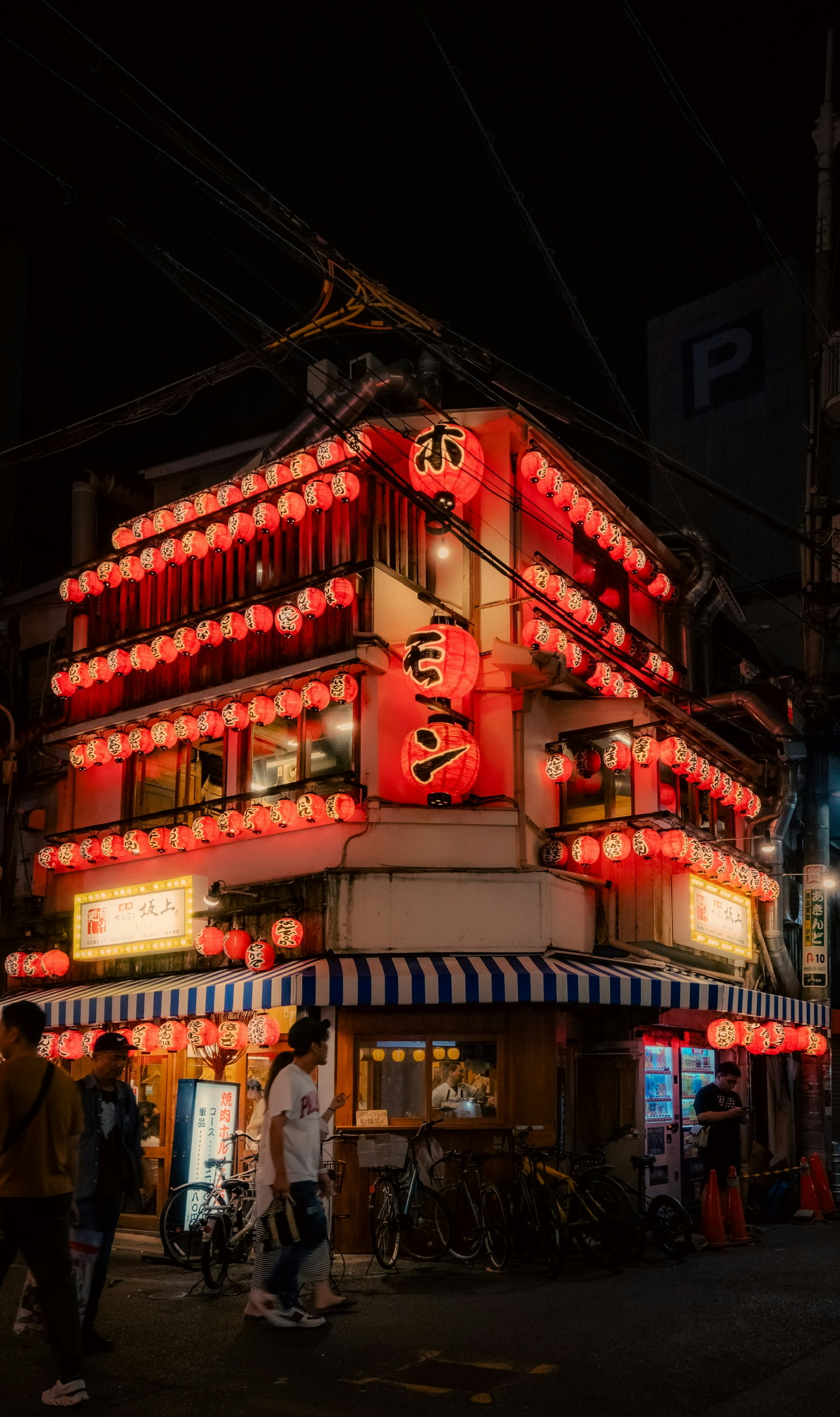 Japanese izakaya building adorned with red lanterns in a nighttime street scene