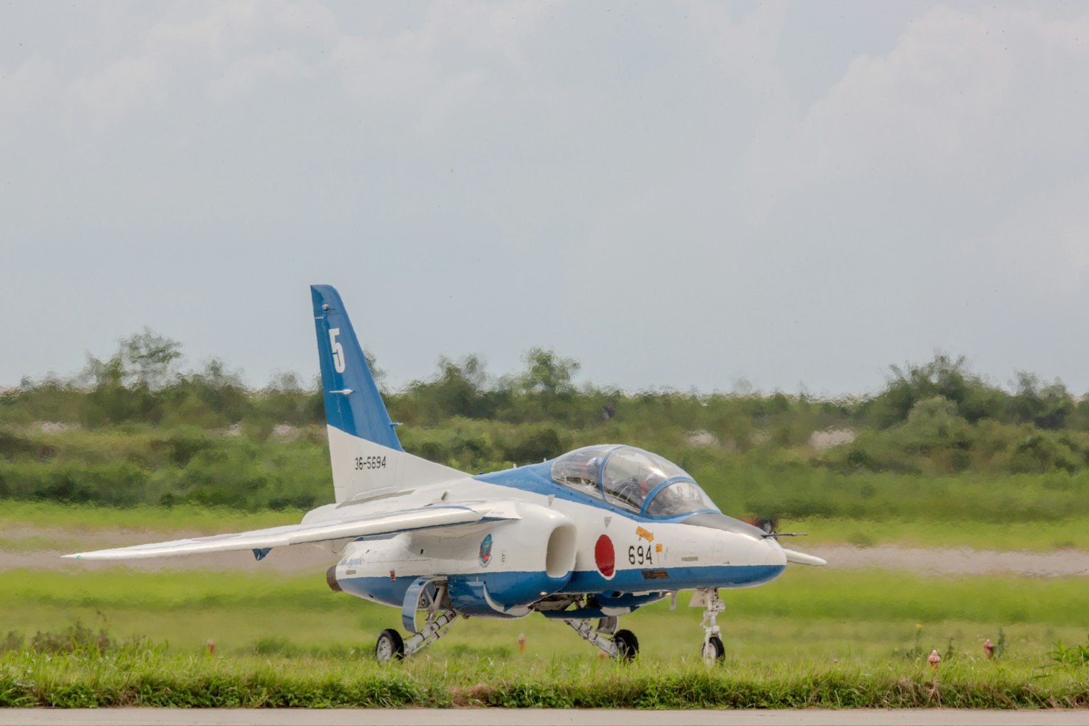 Máy bay màu xanh đang lăn bánh trên đường băng