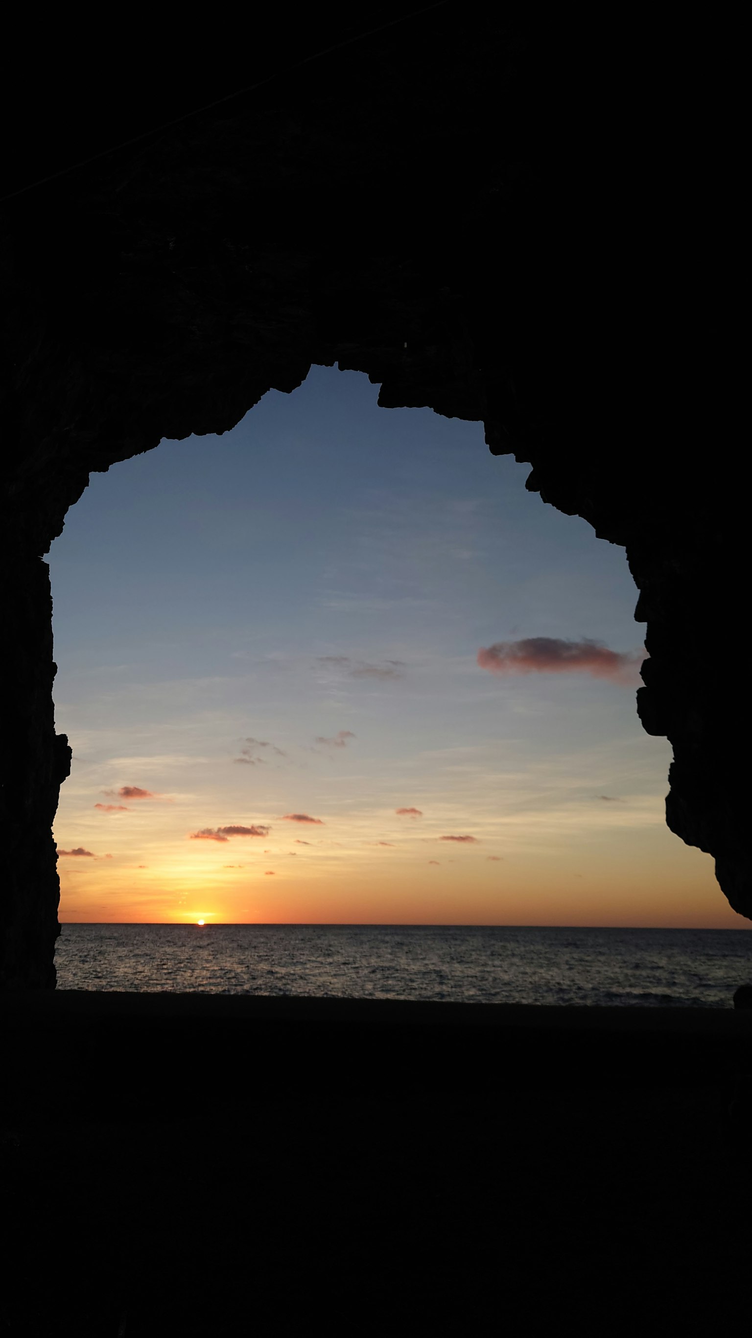 Beautiful sunset and sea view through a rocky arch