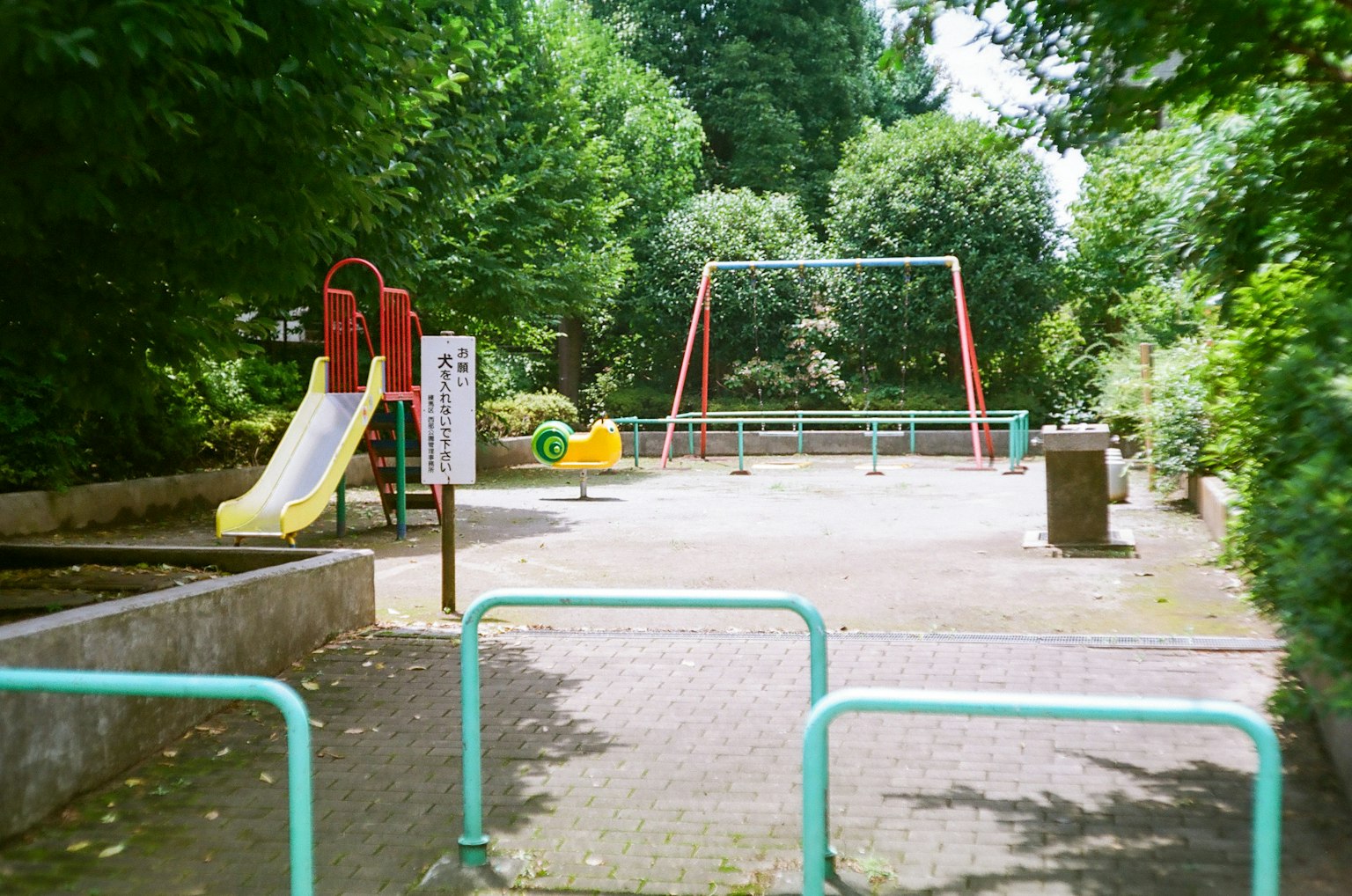 Parco giochi con scivolo giallo altalene rosse e attrezzature verdi