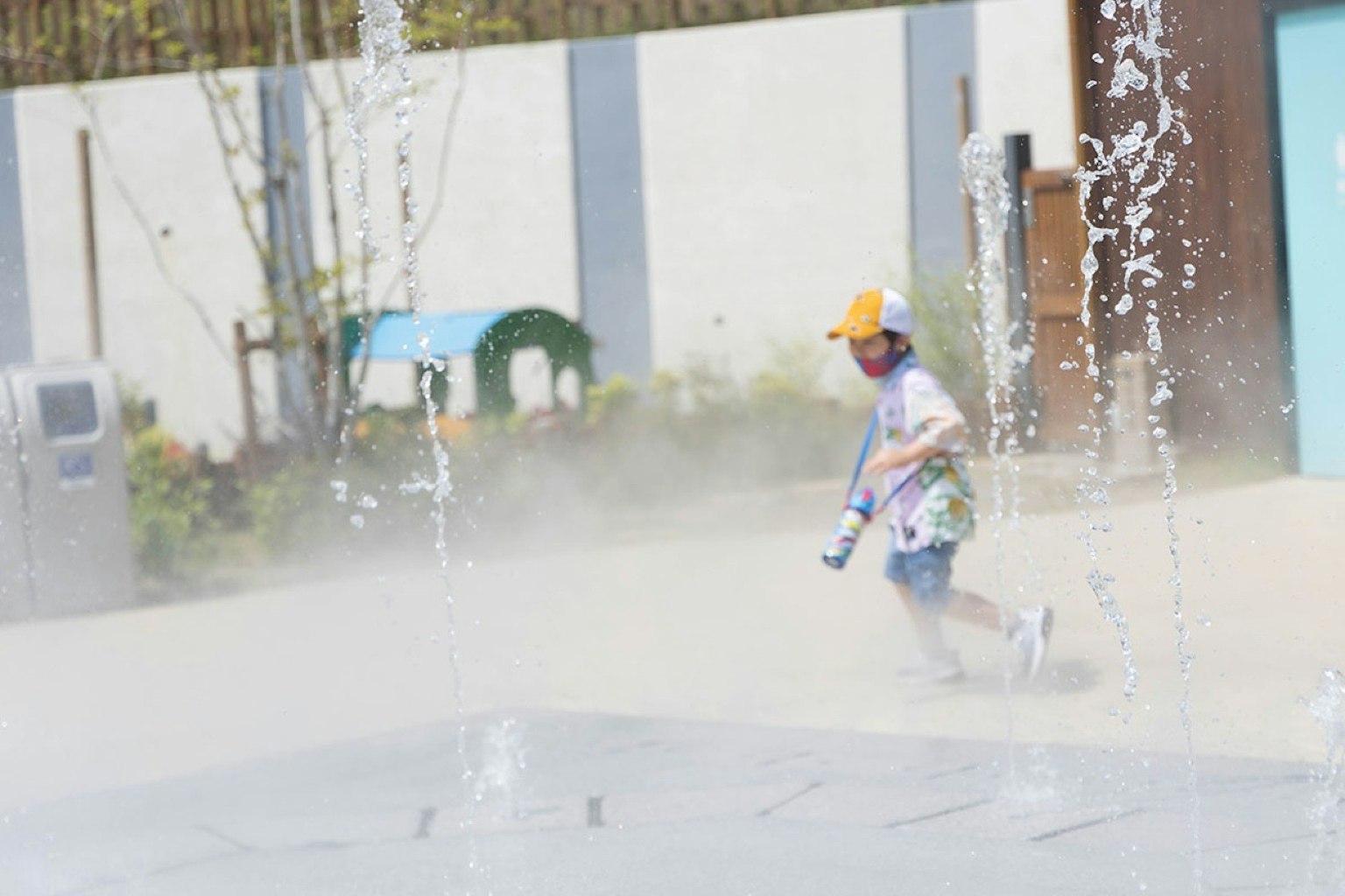 A child running through a fountain with splashes and a joyful expression