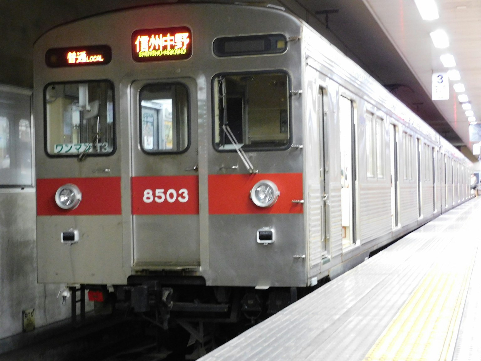 赤いストライプのある銀色の地下鉄車両が駅に停車している