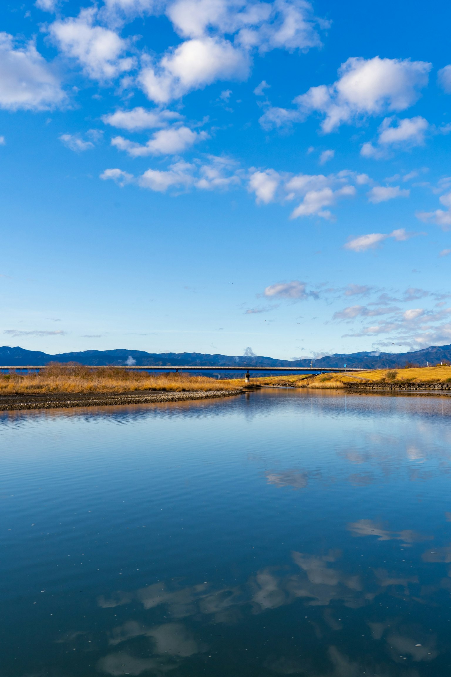 Paysage de rivière serein avec ciel bleu et nuages réfléchis