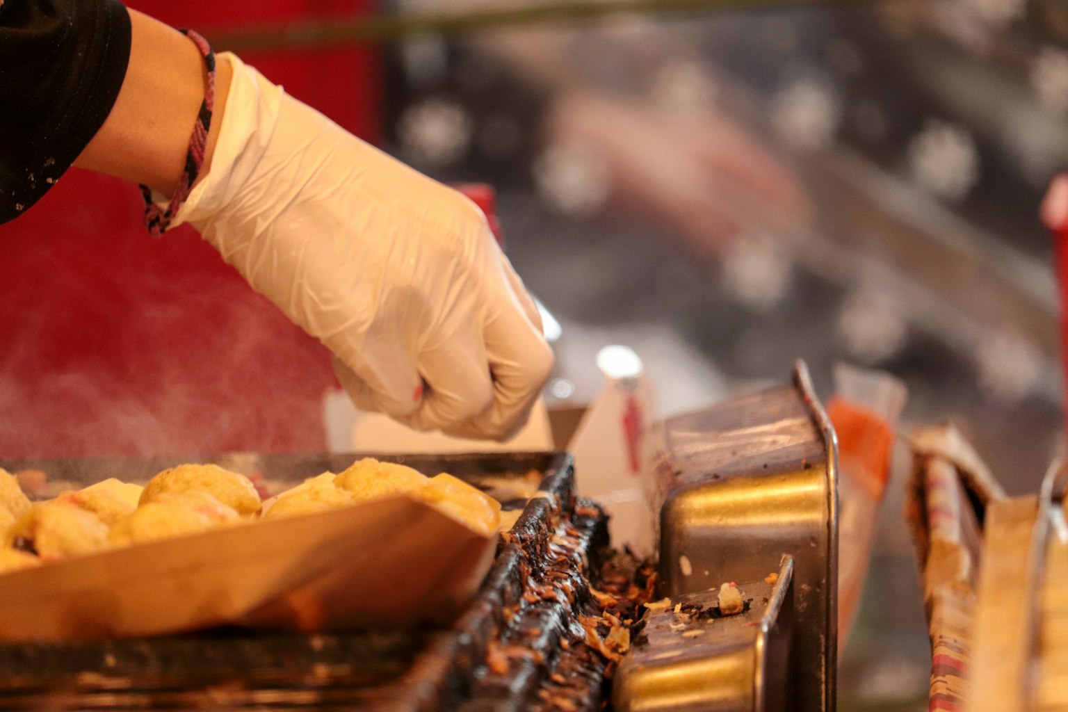 Una mano guantata che cosparge condimento su cibo grigliato