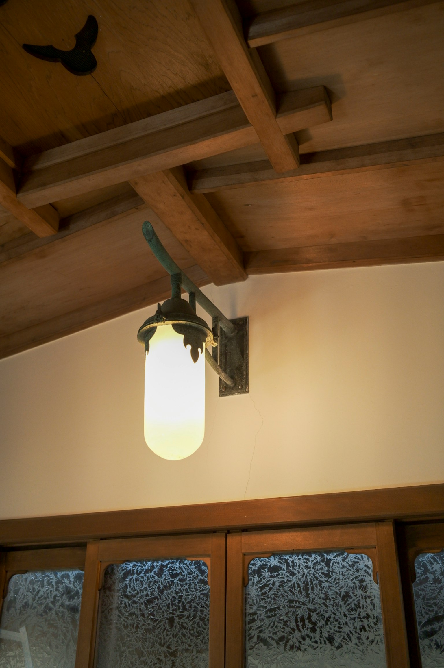Lampada bianca con supporto nero montata su soffitto in legno