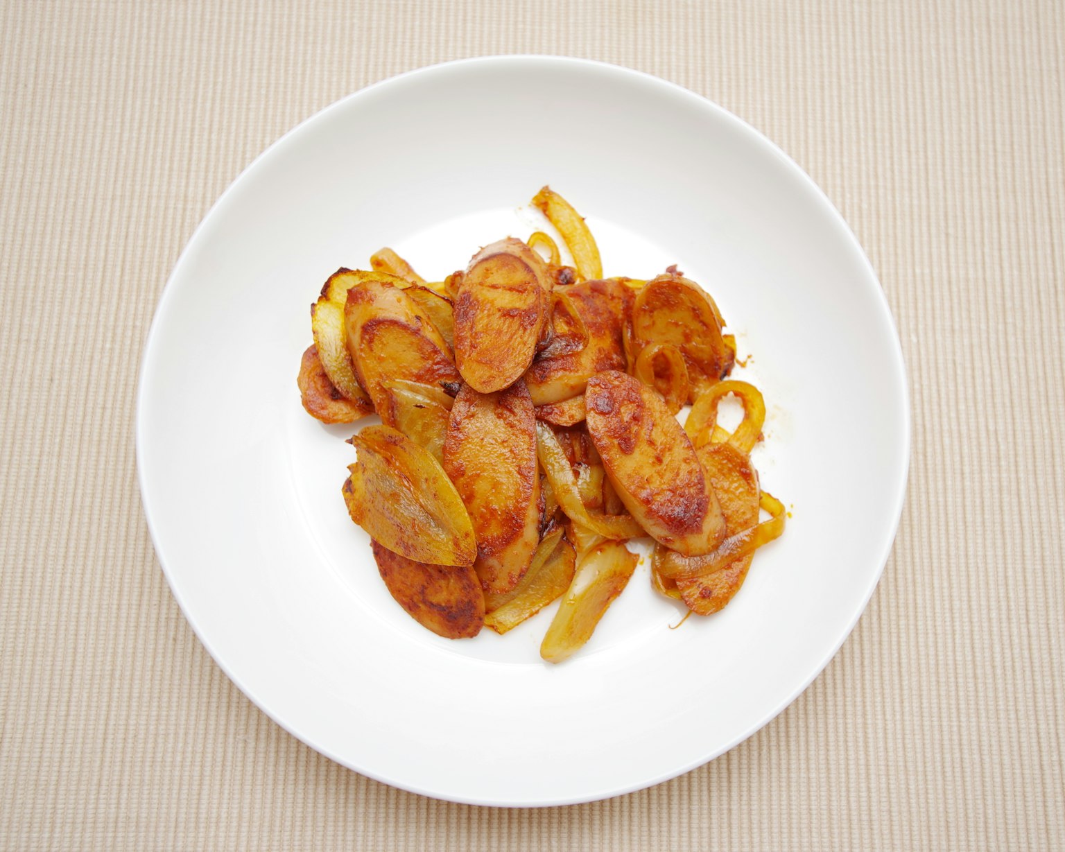 Sautéed potato and onion slices served in a white bowl