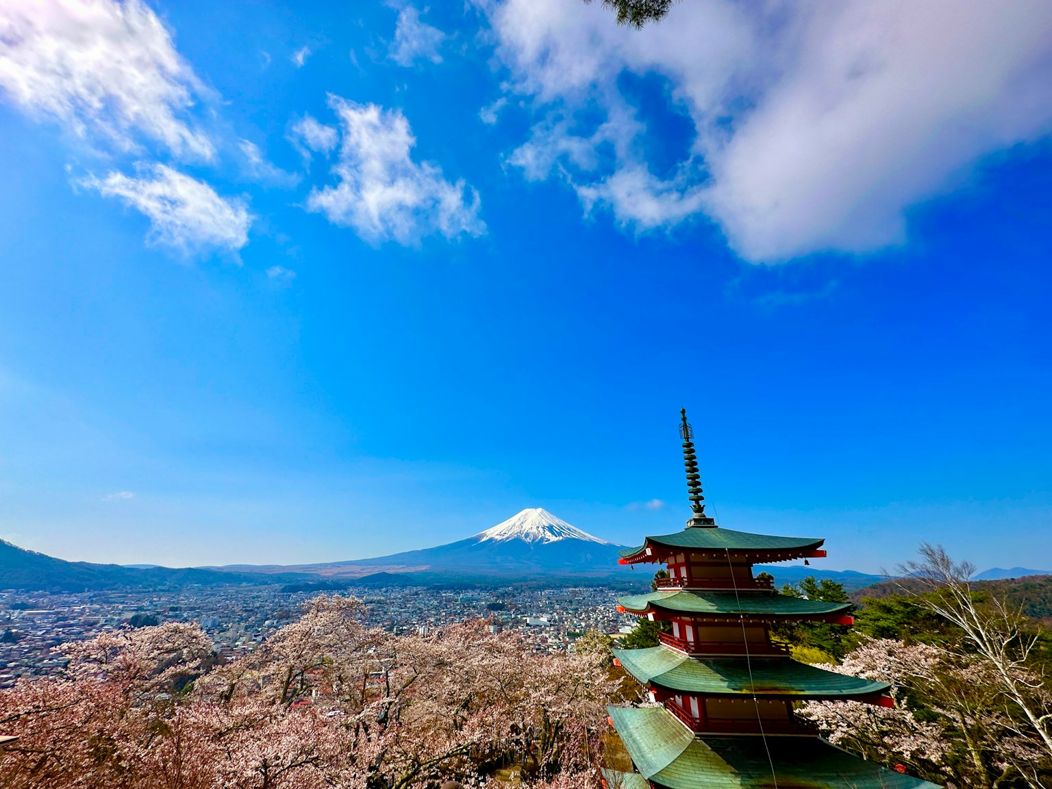 Vista de una pagoda con el monte Fuji y cerezos en flor de fondo